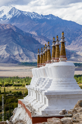 Many Buddhist white stupas and Himalayas mountains in the background near Shey Palace in Ladakh, India.