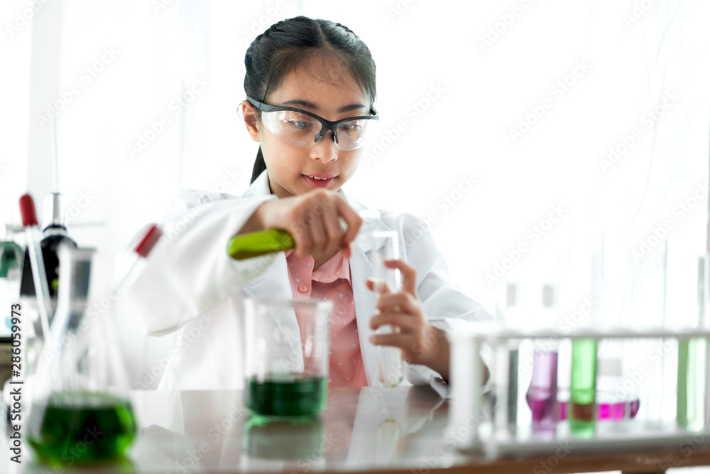 Teenage girl students learning and doing a chemical experiment and holding test tube in hands in science class on the table.Education concept Teenage girl students learning and doing a chemical experiment and holding test tube in hands in science class on the table.Education concept
