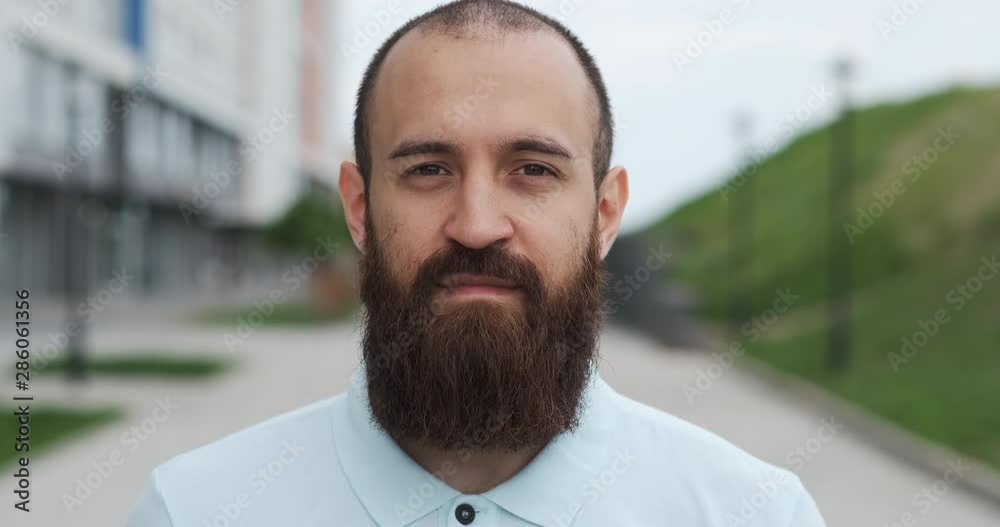Against background of new houses and green lawn man stands, looking at camera Against background of new houses and green lawn man stands, looking at camera