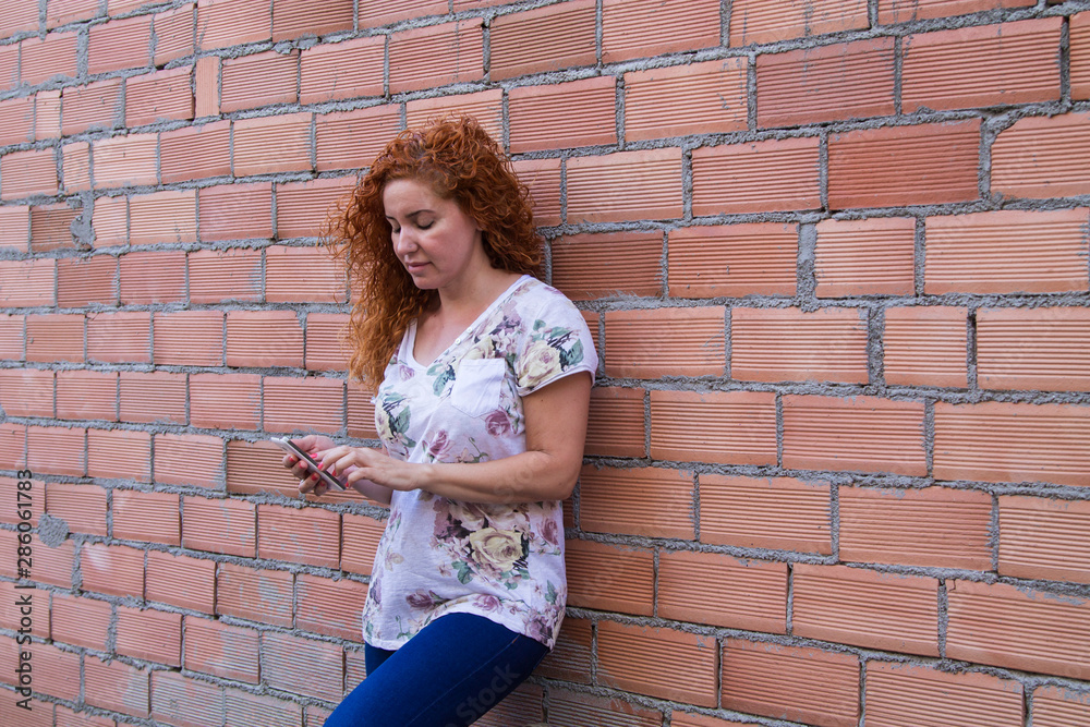 woman with her mobile phone on the brick wall