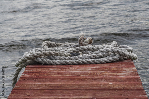 Shabby rope lies on a red wooden pier © Макар Мосин