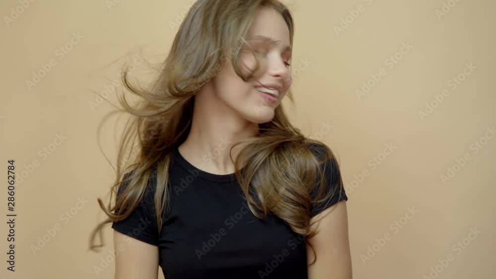 closeup portrait of young wooman posing to a camera with blowed out hair on grey closeup portrait of young wooman posing to a camera with blowed out hair on grey
