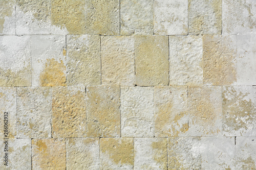 Stone wall made of yellow rectangular blocks background.