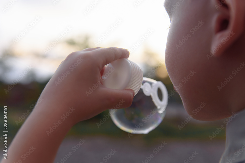 Fototapeta premium Little boy blowing bubbles. The concept of lifestyle and childhood.