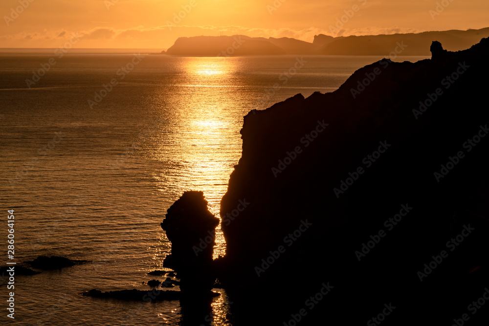 Sunrise reflection on the sea with steep coastline