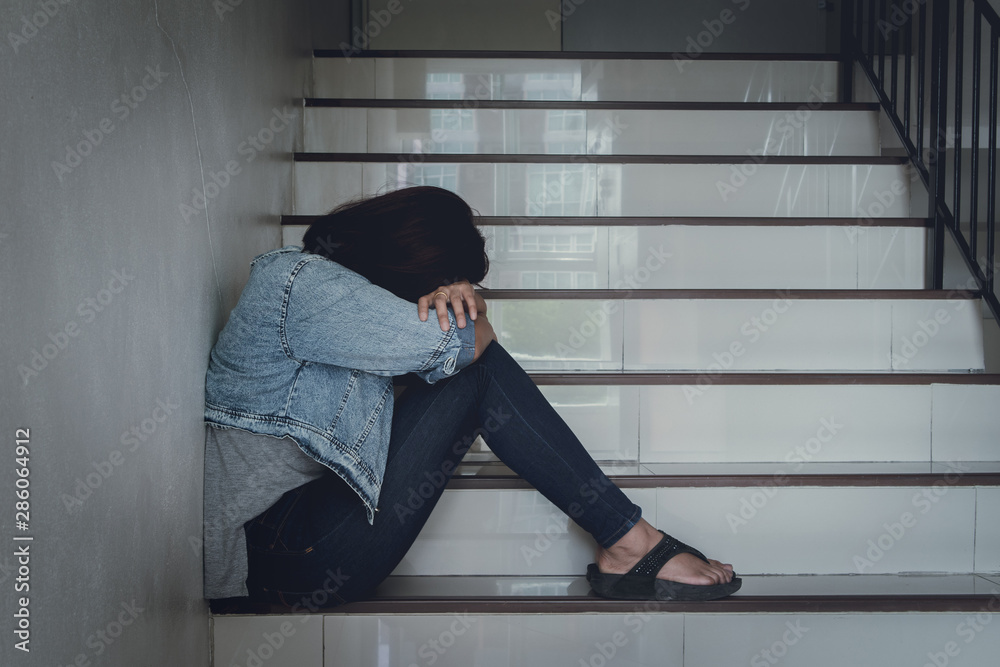 Close up sad woman sitting at staircase in apartment.Sad,depression concept.