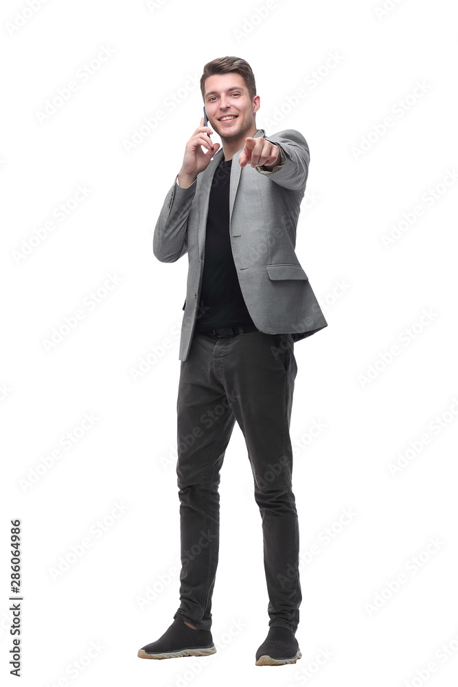 Naklejka premium handsome man talking to a mobile phone and pointing to a copy of the space