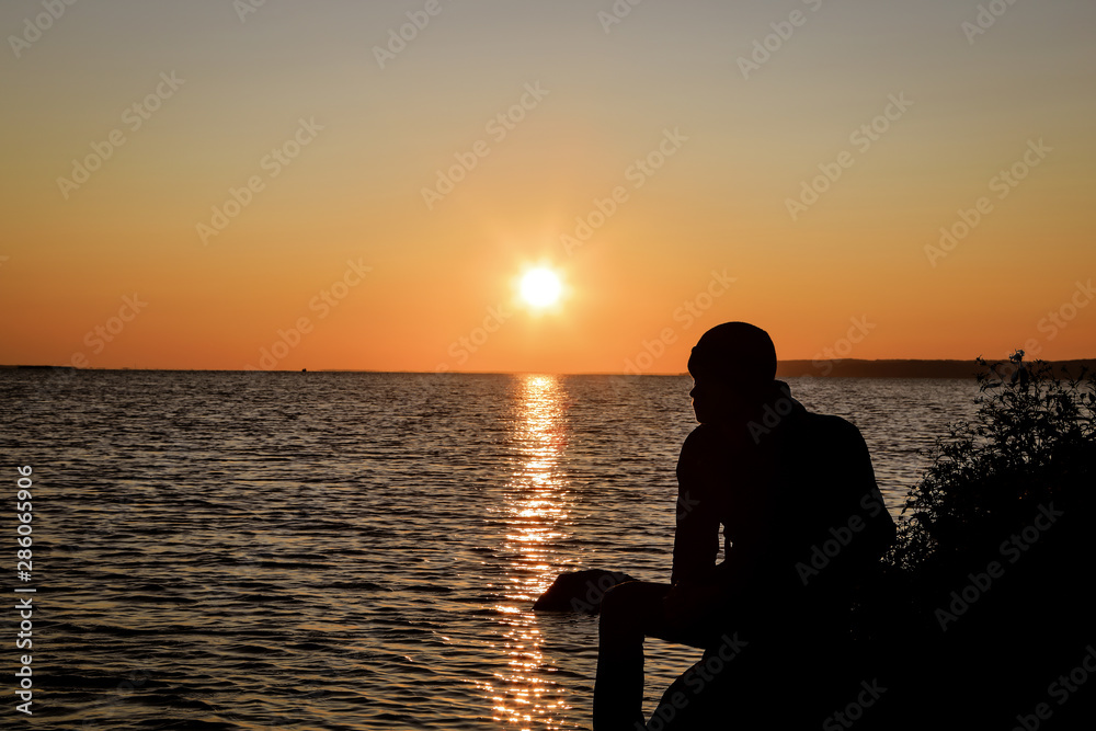 a guy sits on a mountain at sunrise against the backdrop of a huge river a guy sits on a mountain at sunrise against the backdrop of a huge river