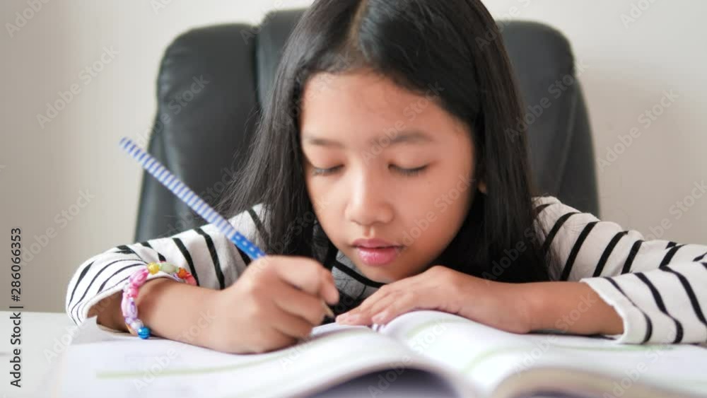 Little Asian girl doing homework with happiness for self learning and home education concept select focus shallow depth of field Stock ビデオ | Adobe Stock