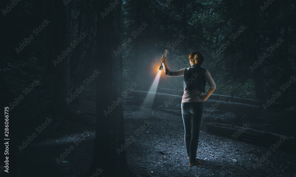 Young woman holding a flashlight - obrazy, fototapety, plakaty 