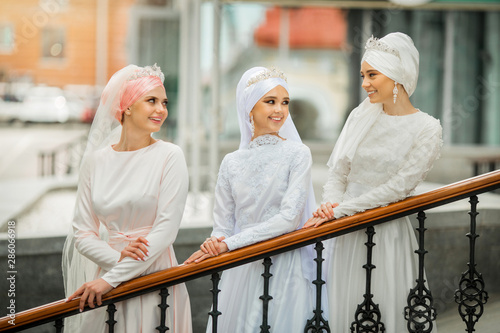 three beautiful young women in national festive white muslim dresses 