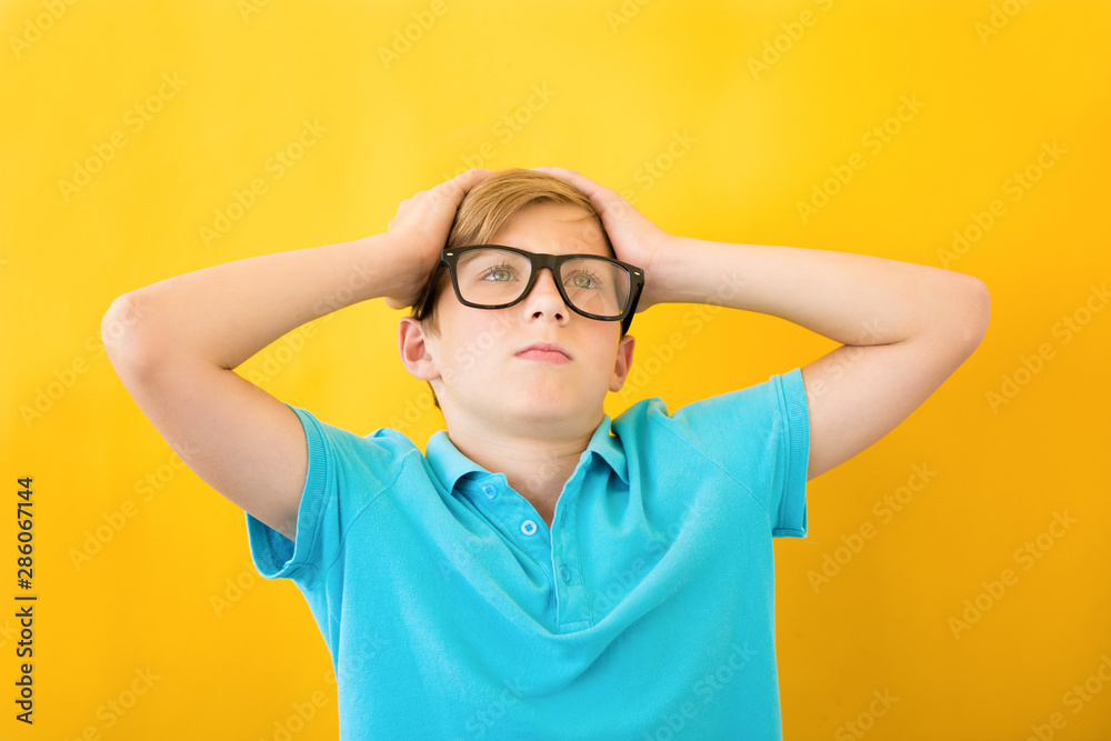 Frustrated boy holding his head on a yellow background. Study, difficulties and problems concept Frustrated boy holding his head on a yellow background. Study, difficulties and problems concept