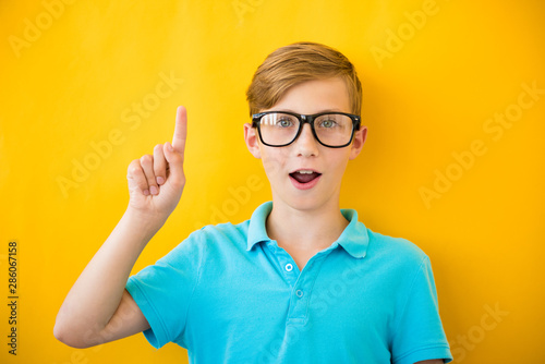 Portrait of stylish little boy with finger pointed up. Kid on yellow blackboard. Success  bright idea  creative ideas and innovation technology concept
