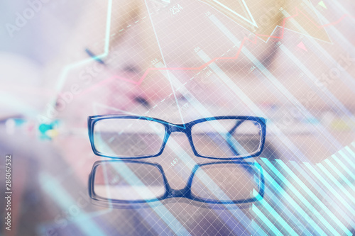 Hand taking notes in notepad. Forex chart holograms in front. Concept of research. Double exposure