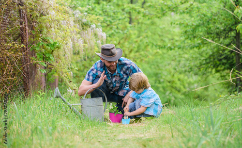 happy earth day. Family tree nursering. father and son in cowboy hat on ranch. watering can, pot and hoe. Garden equipment. Eco farm. small boy child help father in farming. Transplanting plant