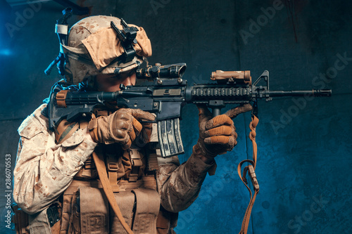 American private military contractor shooting a rifle. Studio shot