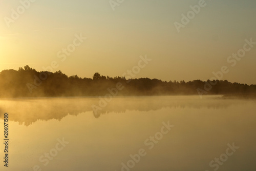 sunrise above a river on foggy summer morning, the sky reflections in the water, misty reflection in steaming water, Salaca river, Latvia 