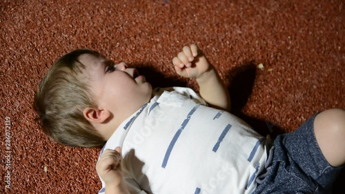 child naughty on the floor in the evening park. Low light, high gain.