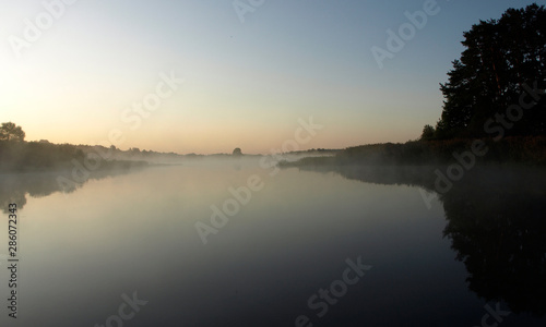 sunrise above a river on foggy summer morning  the sky reflections in the water   misty reflection in steaming water  Salaca river  Latvia 