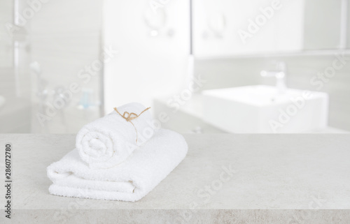 White towels on table in defocused bathroom with copy space