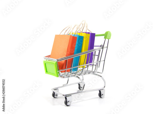 Trolley cart with colorful paper shopping bags isolated on white background. Creative idea for shopping online, sale, supermarket, discount promotion and summer sale concept.