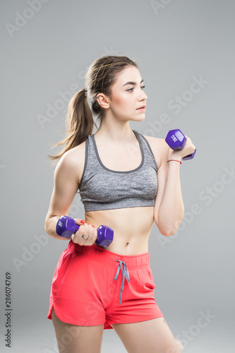Young girl holding a dummbell on white background photo