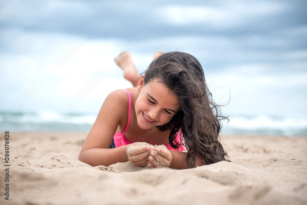 Pretty little girl playing with the sand on the beach Pretty little girl playing with the sand on the beach