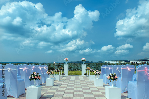Exit registration of the newlyweds, wedding ceremony under open sky. Seating guests overlooking the river. Rows of chairs with white capes, wedding arch, floral design.