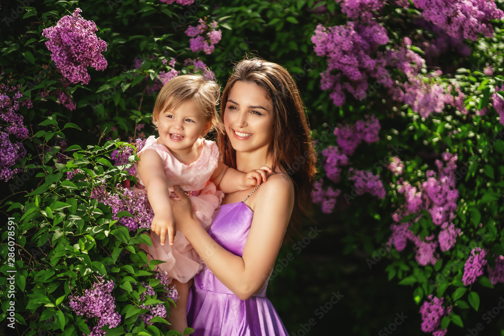 Happy mom and her little daughter having fun on a walk outdoor. Flowering trees at the park. Spring time Happy mom and her little daughter having fun on a walk outdoor. Flowering trees at the park. Spring time