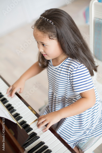 Kazakh asian little girl learning to play piano