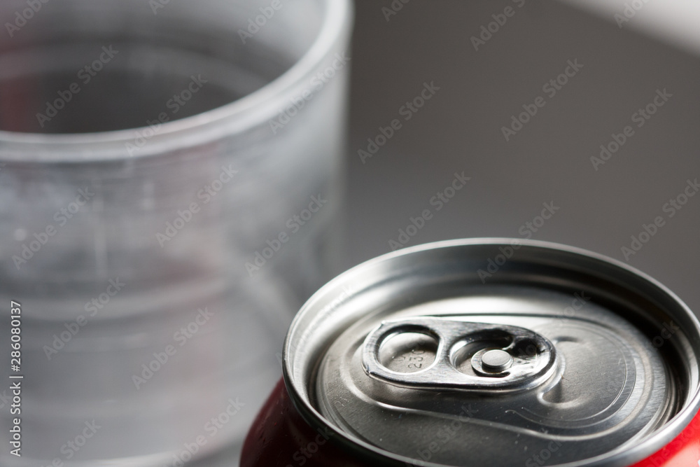 Can of cold unopened soda with a glass next to it. Cold soft drinks with excess sugar, closed. Not healthy. Cold drinks. Can of cold unopened soda with a glass next to it. Cold soft drinks with excess sugar, closed. Not healthy. Cold drinks.