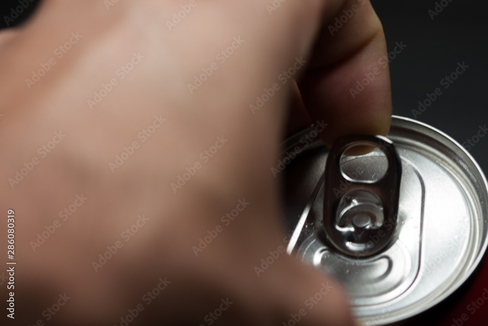 Fototapeta premium Hand opening a can of cold soda. Finger making strength to open the can. Cold drinks.