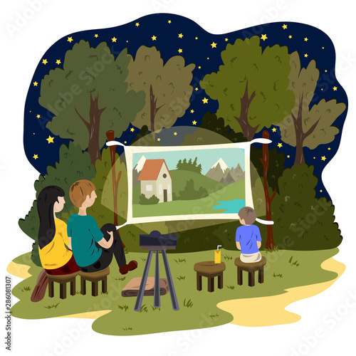 A young couple and a little boy are watching an outdoor movie. Street cinema