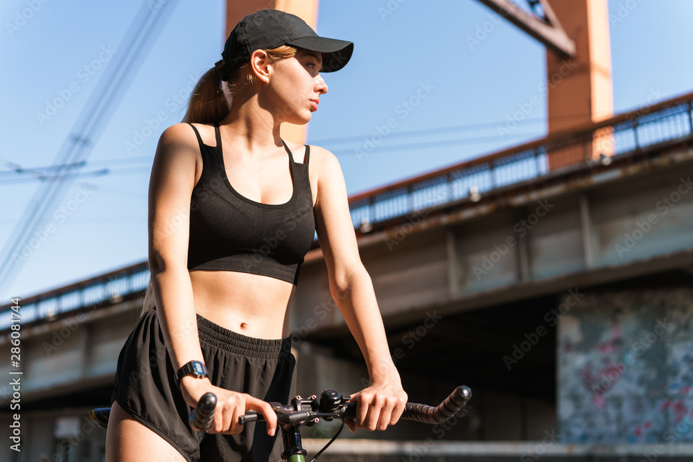 Image of attractive blonde woman riding bicycle through city street on summer sunny day Image of attractive blonde woman riding bicycle through city street on summer sunny day