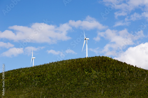 Two wind turbines on Mount Miller seen against blue sky during a beautiful sunny day, Murdochville, Quebec, Canada