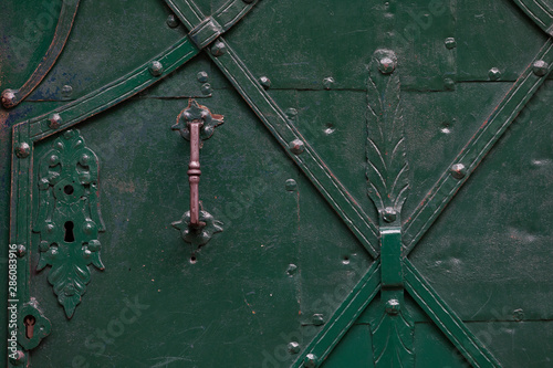 full frame of an historic green iron entrance door with door knob and lock in Salzburg city