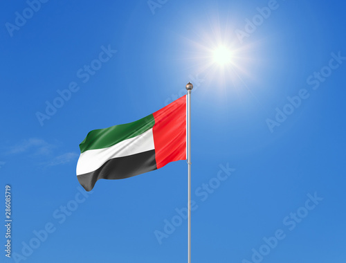 3D illustration. Colored waving flag of United Arab Emirates on sunny blue sky background.
