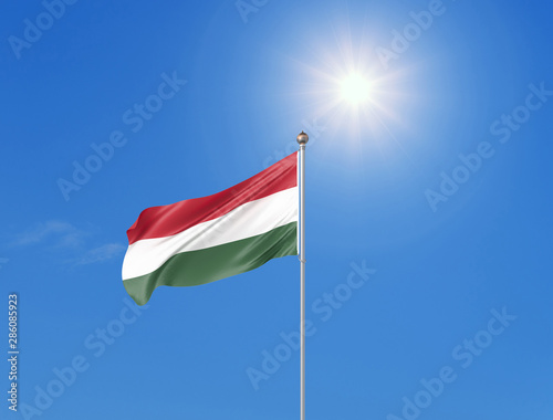3D illustration. Colored waving flag of Hungary on sunny blue sky background.