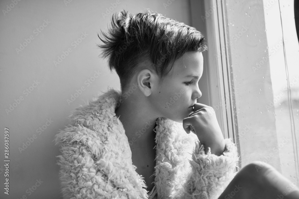 Portrait of a stylish girl who is sitting by the window