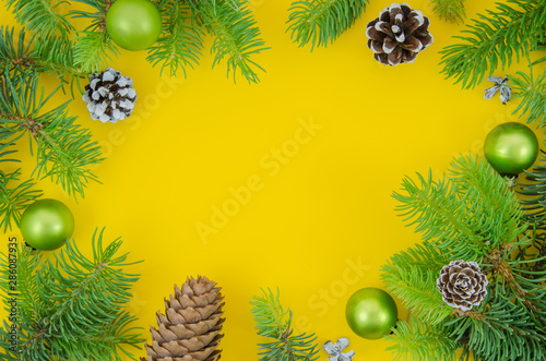 Christmas frame mockup. Pine cones  fir branches and Christmas balls on yellow background. New year flat lay  top view with copy space