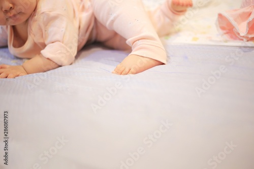 baby crawling and rolling around on the bed. soft and tenderness small baby feet laying on the soft bed sheets. growing up in a loving comfort family.