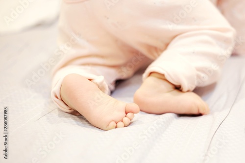 baby crawling on the bed. cute little baby feet pushing. soft and tenderness family concepts.