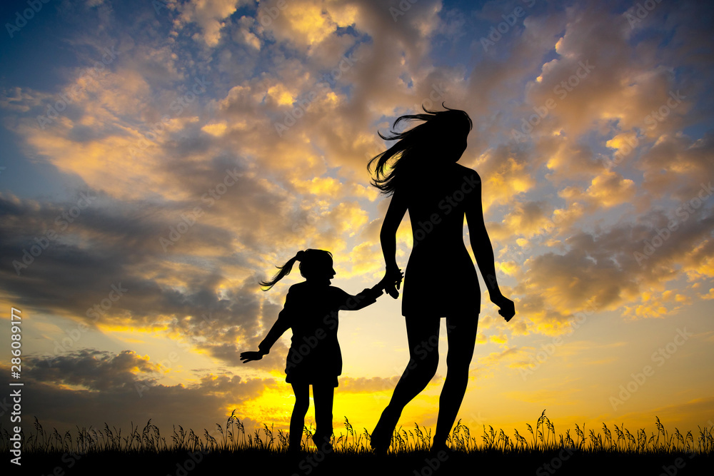 girl runs with her daughter at sunset
