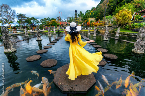 Woman standing in pond with colorful fish at Tirta Gangga Water Palace in Bali, Indonesia. photo