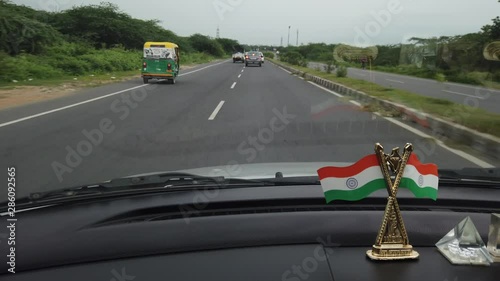 Time-lapse passenger's point-of-view shot from a moving vehicle with Indian national flags in foreground on the dashboard of the car while being driven on highways in Delhi & Gurgaon, India 