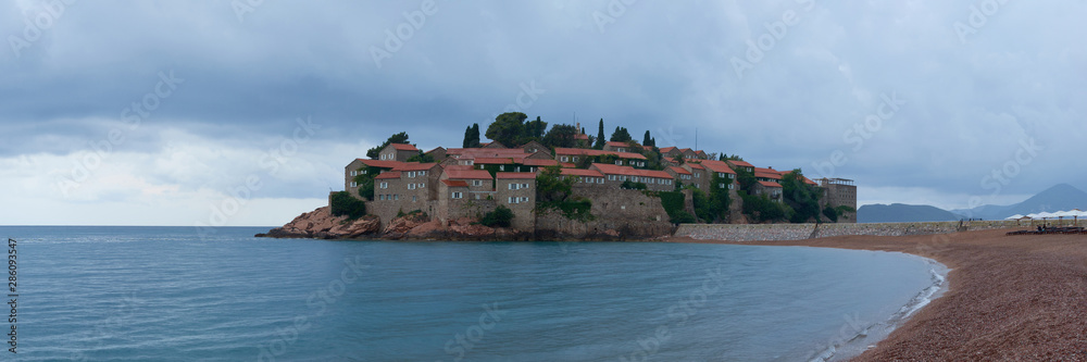 View of Sveti Stefan from the beach on a cloudy day.
