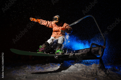 Male snowboarder dressed in a orange sportswear jumping from the funicular