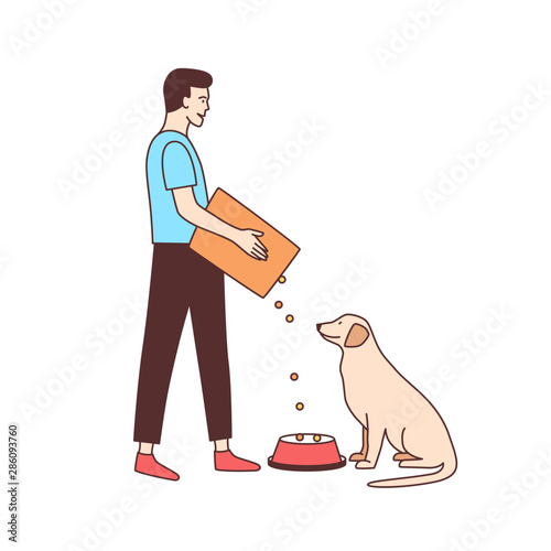 Cute male volunteer feeding stray dog in animal shelter or pound