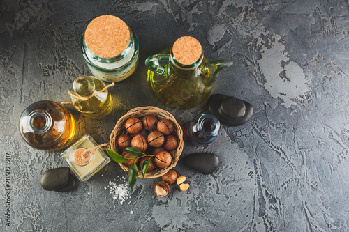 Natural macadamia oil in a glass bottle with macadamia nuts