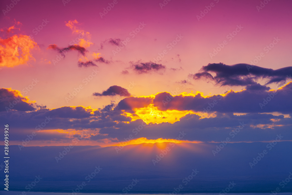 Colorful cloudy sky at sunset. Sunset over the mountains. Pink purple gradient color. Abstract nature background. Sunset sky texture